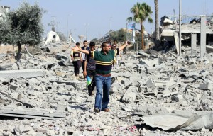 Palestinians walk past houses destroyed by Israeli airstrikes and shelling in Khuzaa, 3 August. (Ramadan El-Agha / APA images) 